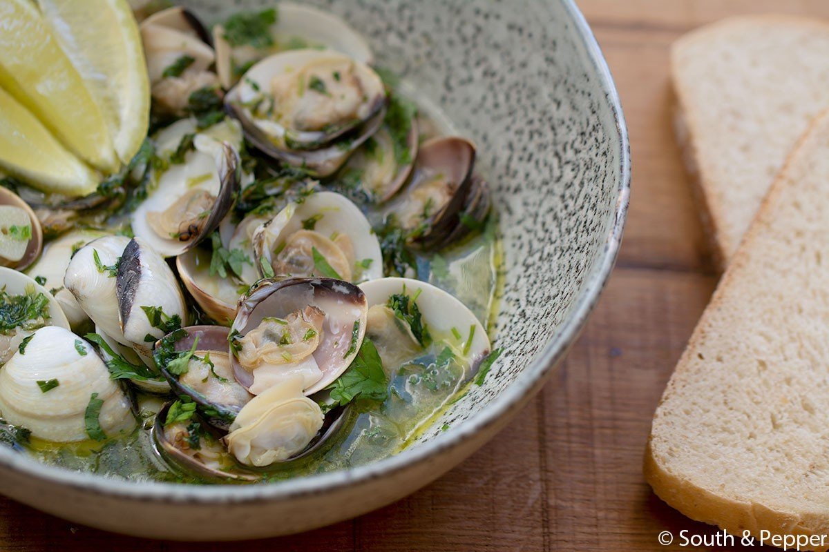 Venusschelpen in een kom met kruiden en citroen