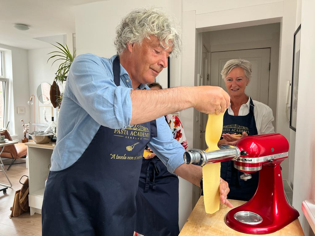 deelnemer maakt zelf pasta op een pastamachine en houdt een pastavel vast