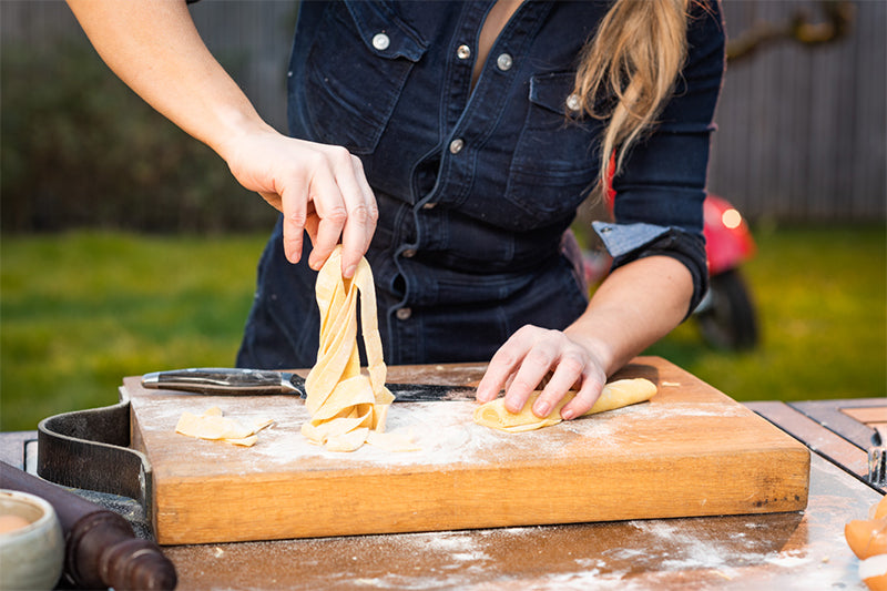 Sarah Puozzo maakt fettuccine en houdt het vast boven een houten plank
